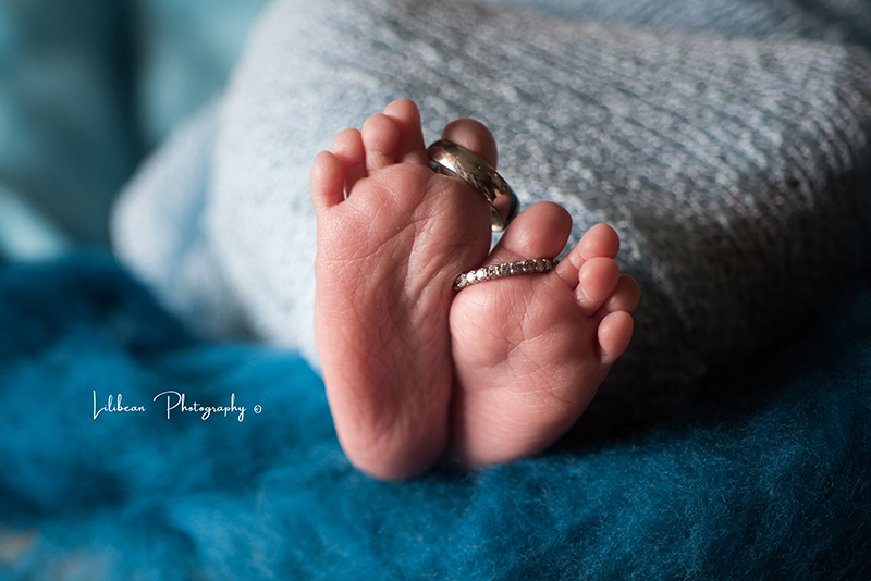 Newborn baby feet with mom and dad wedding bands on toes