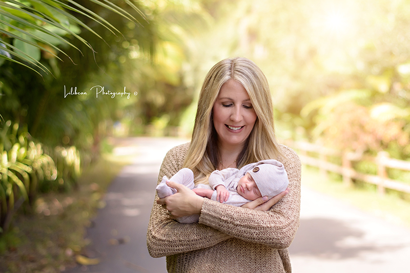 newborn baby held by mom outdoors backlit 