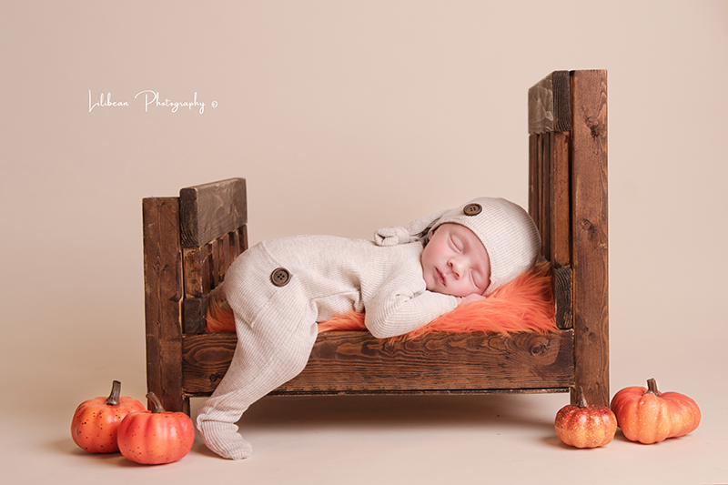 Newborn Baby in Wooden bed with small pumpkins