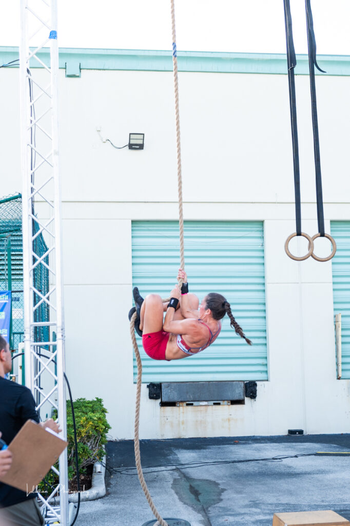 woman performing a rope climb during a crossfit competition