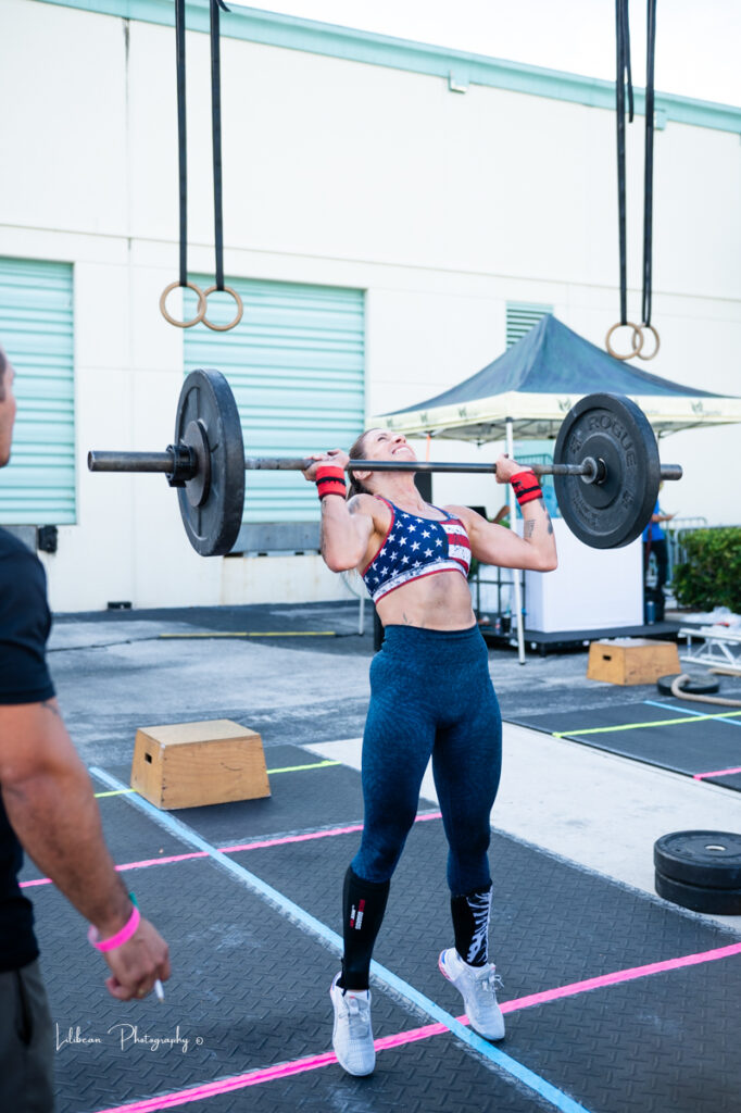woman lifting barbell during crossfit competition  wearing American flag sports bra