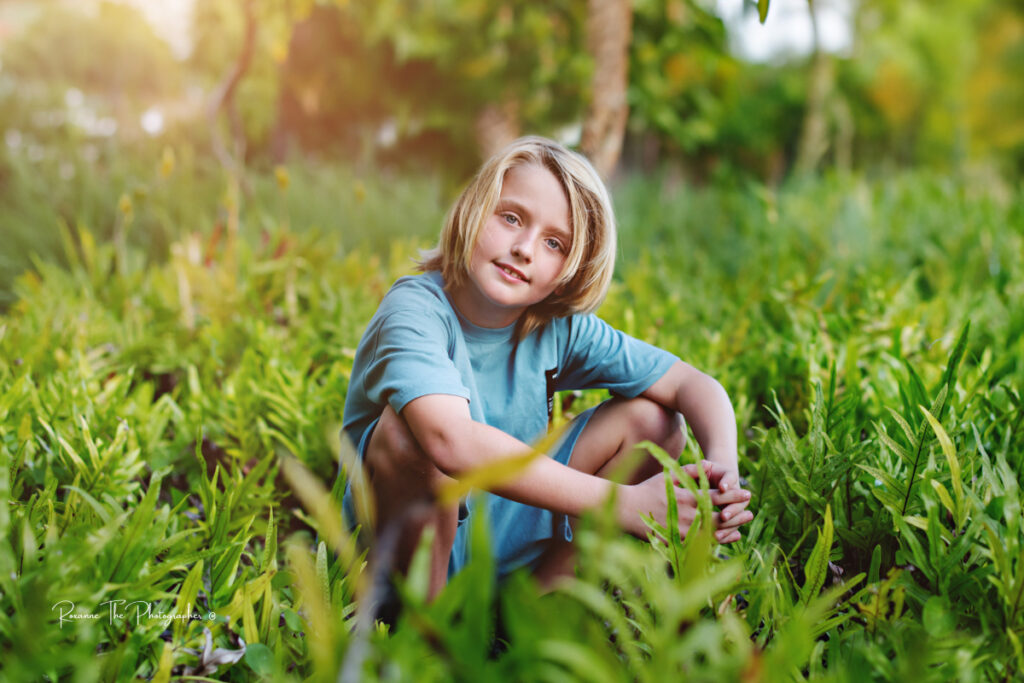 Little blond hair boy sitting in green field